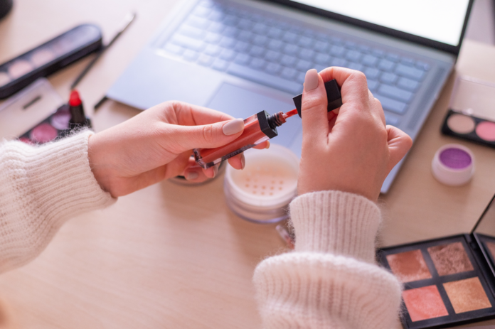 Woman holding lip gloss about to do a live tutorial for lip gloss business ideas blog post.png